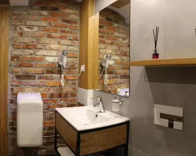 a bathroom with a sink and a brick wall at Pokoje Wieliczka in Wieliczka