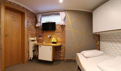 a small room with a bed and a desk in it at Pokoje Wieliczka in Wieliczka