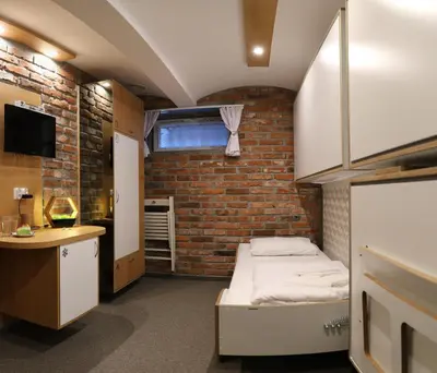 a small room with a bed and a brick wall at Pokoje Wieliczka in Wieliczka