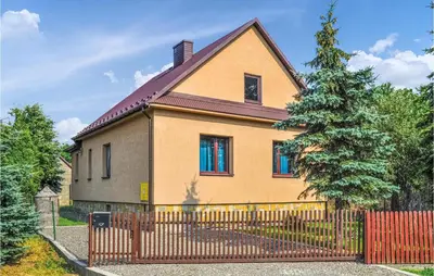 a house with a fence and a tree at One-Bedroom Holiday Home In Biadoliny Szlachecki in Biadoliny Szlacaheckie