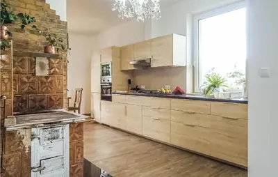 a kitchen with wooden cabinets and a large window at One-Bedroom Holiday Home In Biadoliny Szlachecki in Biadoliny Szlacaheckie