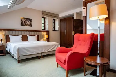 a bedroom with a bed and a red chair at Grand Sal in Wieliczka