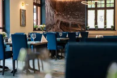 a dining room with tables and blue chairs at Grand Sal in Wieliczka