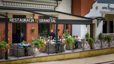 a group of people sitting on a balcony of a restaurant at Grand Sal in Wieliczka