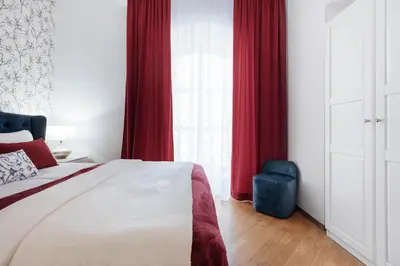 a bedroom with red curtains and a bed with a blue stool at Tomasza 20 Apartments in Kraków