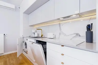 a kitchen with white counters and a sink at NY Residence Apartments Wrocławska Cracow by Renters Prestige in Kraków