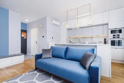 a blue couch in a living room with a kitchen at NY Residence Apartments Wrocławska Cracow by Renters Prestige in Kraków