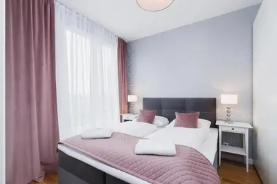 a bedroom with a large bed with white sheets and pink pillows at NY Residence Apartments Wrocławska Cracow by Renters Prestige in Kraków