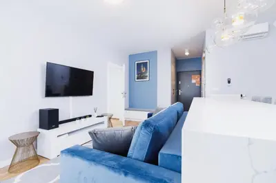 a living room with a blue couch and a flat screen tv at NY Residence Apartments Wrocławska Cracow by Renters Prestige in Kraków