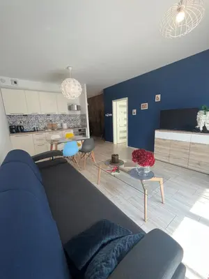 a living room with a blue couch and a kitchen at Way2Stay Browar Lubicz in Kraków