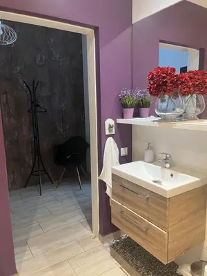 a bathroom with a sink and flowers on a purple wall at Way2Stay Browar Lubicz in Kraków