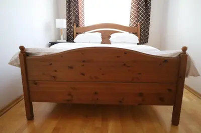 a wooden bed with white sheets and pillows at Cosy and Comfortable Apartment in Cracov in Kraków