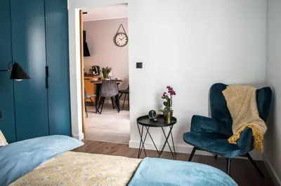 a bedroom with a blue chair and a table at Augustiańska in Kraków