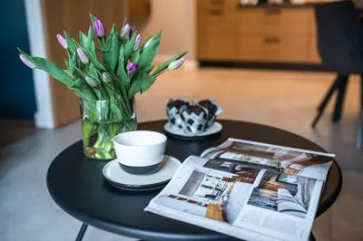 a table with a vase of flowers and a newspaper at Augustiańska in Kraków