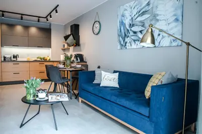 a living room with a blue couch and a kitchen at Augustiańska in Kraków