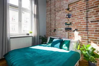 a bed in a room with a brick wall at Discover Krakow Apartments - 3 Rakowicka St - Amazing Loft near Main Station - Netflix in Kraków