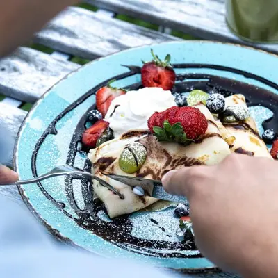 a person eating a dessert with berries on a plate at Discover Krakow Apartments - 3 Rakowicka St - Amazing Loft near Main Station - Netflix in Kraków