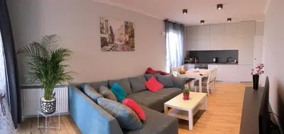 a living room with a blue couch and a kitchen at APARTAMENT LIPSKA 4 in Kraków