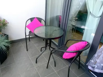 two chairs and a table with pink pillows on a patio at APARTAMENT LIPSKA 4 in Kraków