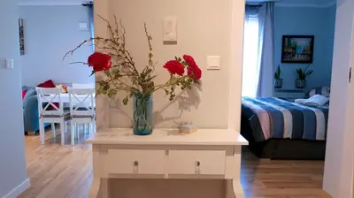 a vase with red flowers on a table in a room at APARTAMENT LIPSKA 4 in Kraków