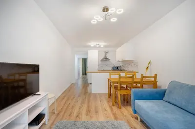 a living room with a blue couch and a kitchen at Apartment Kordiana in Kraków