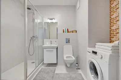 a white bathroom with a toilet and a shower at Apartment Kordiana in Kraków