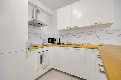 a white kitchen with white cabinets and a counter at Apartment Kordiana in Kraków