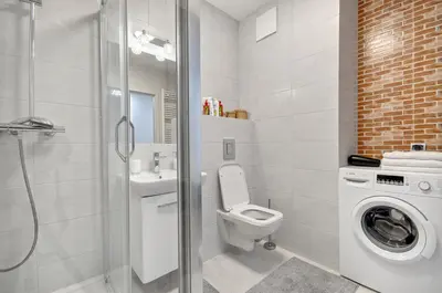a bathroom with a toilet a sink and a washing machine at Apartment Kordiana in Kraków