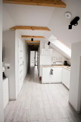an attic kitchen with white cabinets and a wooden ceiling at Spokojna Apartamenty in Trzebinia