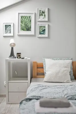a white bedroom with a bed and a night stand at Spokojna Apartamenty in Trzebinia