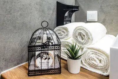a bird cage sitting on a table next to a bed at Rajska 3 ap 206 by Atrium Apartments in Kraków