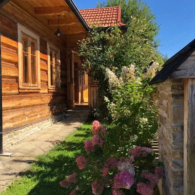 a wooden house with flowers in front of it at Góralskie domy w Łostówce in Łostówka