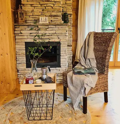 a living room with a fireplace and a chair and a table at Góralskie domy w Łostówce in Łostówka