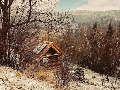 a small cabin on a snowy hill with trees at Góralskie domy w Łostówce in Łostówka
