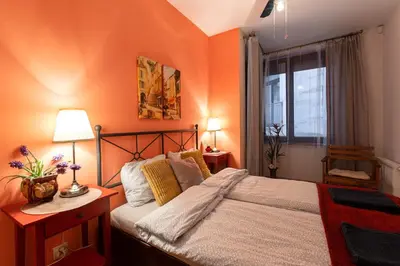a bedroom with orange walls and a bed and a window at Negroni Apartments in Kraków