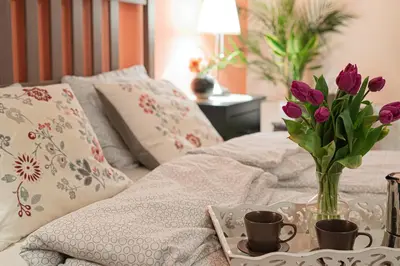 a bed with a vase of purple flowers on a tray at Negroni Apartments in Kraków