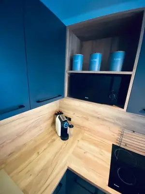 a kitchen counter with blue cabinets and blue cups on it at Apartamenty Majka in Zator