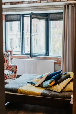 a bed with pillows on it in a room with windows at Singer Retro Studio in Kazimierz in Kraków