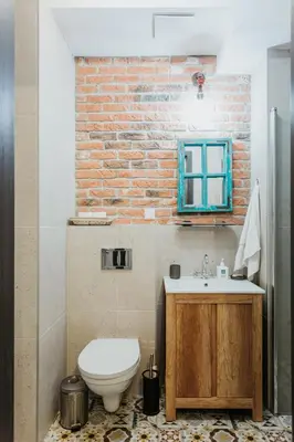 a bathroom with a toilet and a sink and a brick wall at Singer Retro Studio in Kazimierz in Kraków