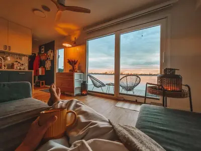 a person laying on a couch in a living room with a large window at Costa del Kryspi Całoroczne Domy na Wodzie in Cholerzyn