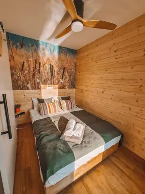 a bedroom with a large bed with a ceiling fan at Costa del Kryspi Całoroczne Domy na Wodzie in Cholerzyn