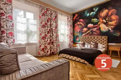 a bedroom with a bed and a couch and a painting at Mikołajska 5 Apartments in Kraków