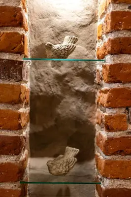 a reflection of a brick wall with two ceramic birds at VINTAGE SENACKA APARTMENTS in Kraków