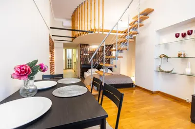 a dining room with a table and chairs and a staircase at VINTAGE SENACKA APARTMENTS in Kraków