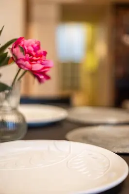a white plate with a pink flower in a vase at VINTAGE SENACKA APARTMENTS in Kraków