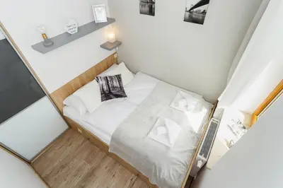 a small room with a bed with white sheets and pillows at Tauron Arena Elegant Apartment Dąbska by Noclegi Renters in Kraków