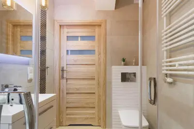 a bathroom with a toilet and a wooden door at Tauron Arena Elegant Apartment Dąbska by Noclegi Renters in Kraków