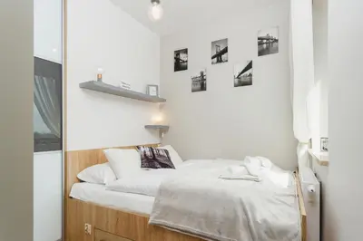 a bedroom with a bed with white sheets and pictures on the wall at Tauron Arena Elegant Apartment Dąbska by Noclegi Renters in Kraków