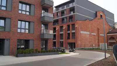 a motorcycle parked in front of a brick building at Beautiful apartment with air conditioning, balcony and underground garage in Kraków