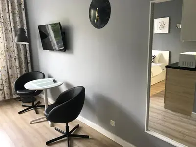 a room with two chairs and a table and a clock at Apartment II GrayFor2 Old Town Kraków in Kraków